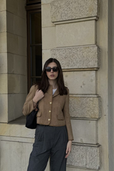 a lady in a white top, a brown wool jacket and a pair of grey pants